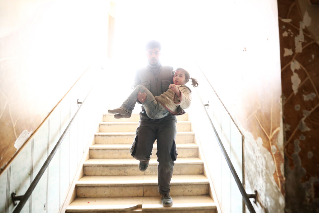 TOPSHOT - A Syrian civil defence volunteer carries a wounded girl as he rushes to a make-shift hospital following reported government airstrike on the rebel-held town of Douma, on the eastern outskirts of the capital Damascus, on February 25, 2017.<br /><br /><br />
Syrian regime forces carried out raids on several areas in the country, targeting mainly the besieged town of Douma, causing the deaths of at least 13 civilians, according to Syrian Observatory for Human Rights. The raids continued despite the United Nations confirmation a few days earlier that Moscow formally asked its ally Damascus to stop launching strikes during the Geneva negotiations, which began earlier in the week. / AFP / Abd Doumany        (Photo credit should read ABD DOUMANY/AFP/Getty Images)