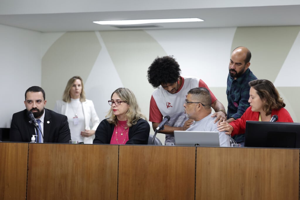 Reginaldo Francisco, pai de Thainara (à direita, sentado), se indignou ao ouvir deputados como Lincoln Drumond, do PL (sentado, à esquerda) defenderem os PMs durante audiência pública sobre o caso (Foto: Daniel Protzner/ALMG)