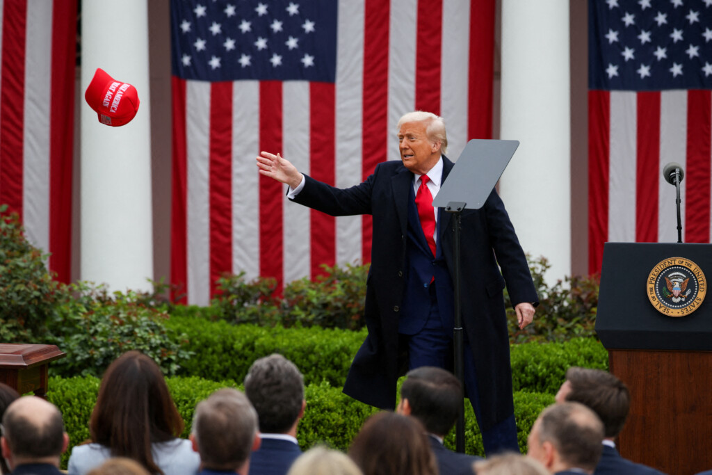 Donald Trump, presidente dos EUA, tenta alcançar um boné MAGA no dia em que discursou sobre tarifas na Casa Branca (Foto: Carlos Barria/Reuters/Folhapress)